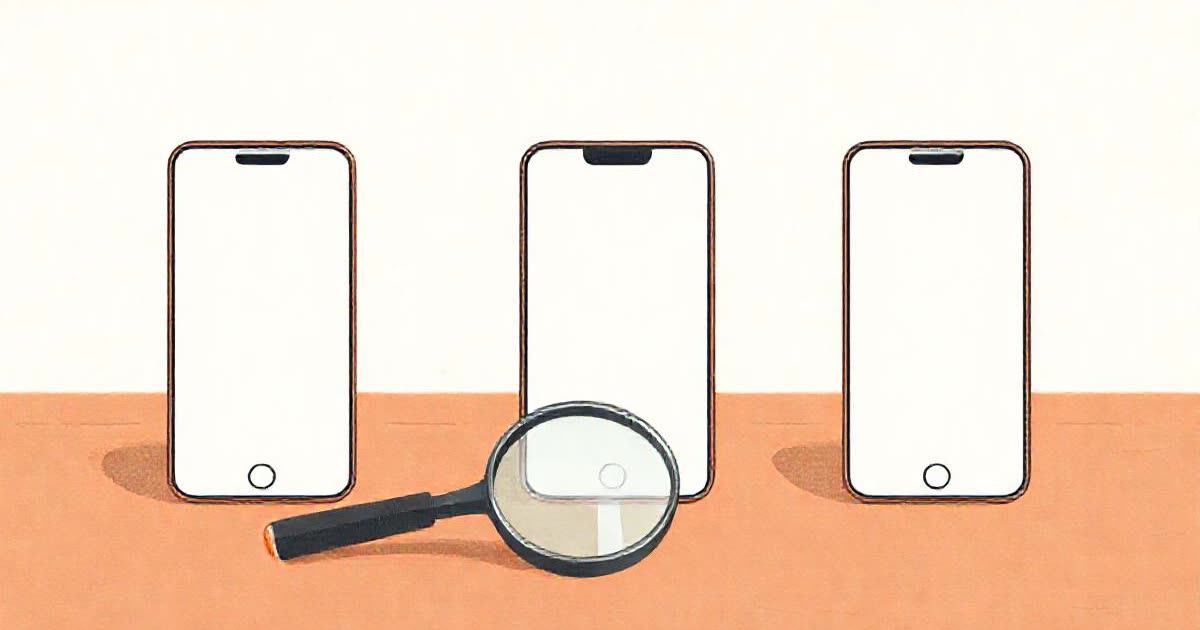 Three different blank smartphones side by side on a table with a magnifying glass.