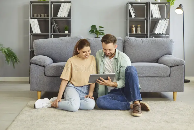 Happy young couple sitting on the floor using a tablet together, smiling and feeling connected
Suggested Caption: From hidden burden to shared understanding
