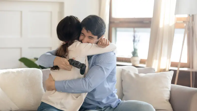 Loving young couple hugging warmly on sofa, feeling relieved and connected after resolving money issues