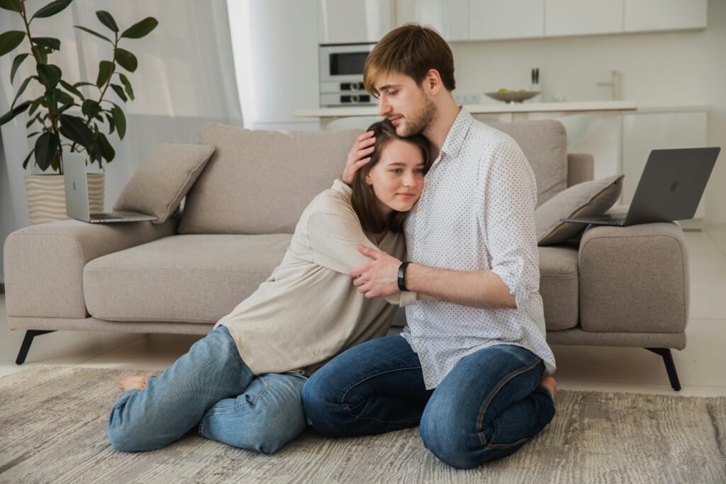 Peaceful young couple hugging affectionately on living room floor – symbolizing restored connection and love after using EvenUS